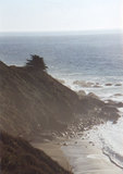 A cliff leading down to the rocky shore, shrouded in mist